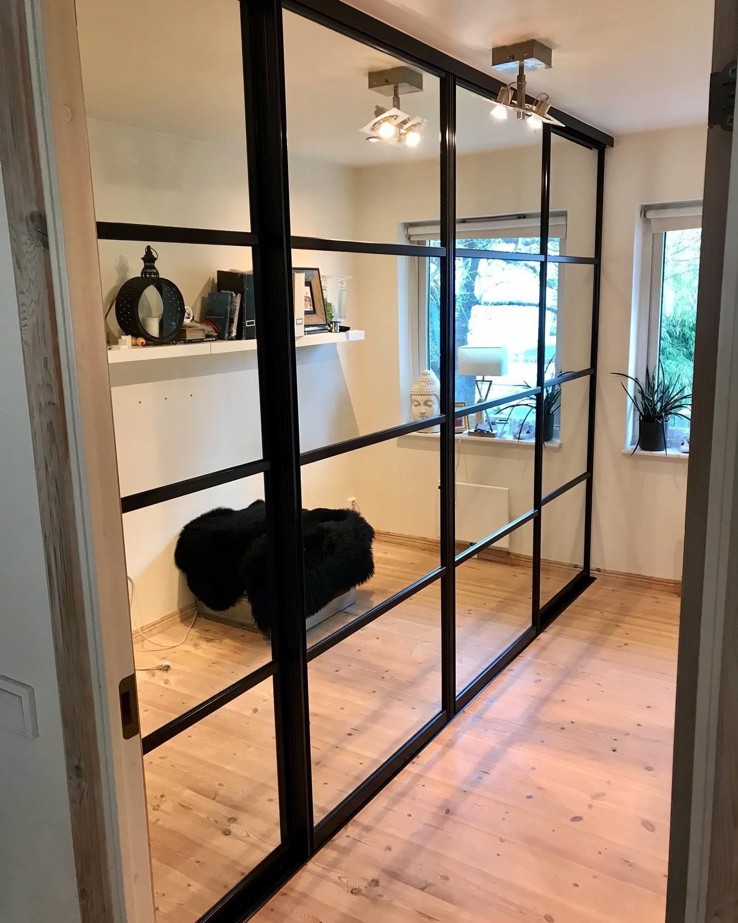 Black-framed glass sliding door in a room with a wooden floor.