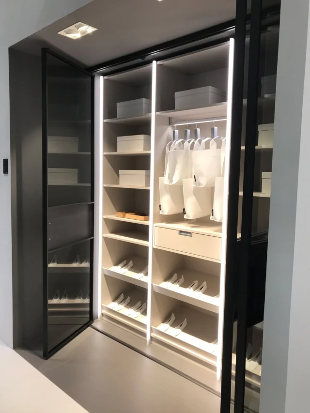 Wardrobe with hinged doors fully open, showing lit shelves, drawers and shoe racks