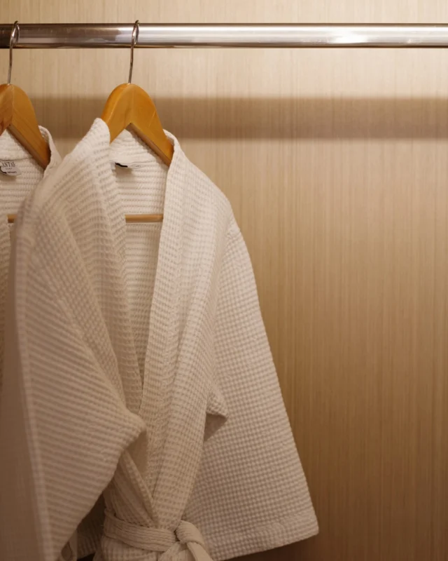 Bathrobes on wooden hangers against a wood-grain wardrobe interior
