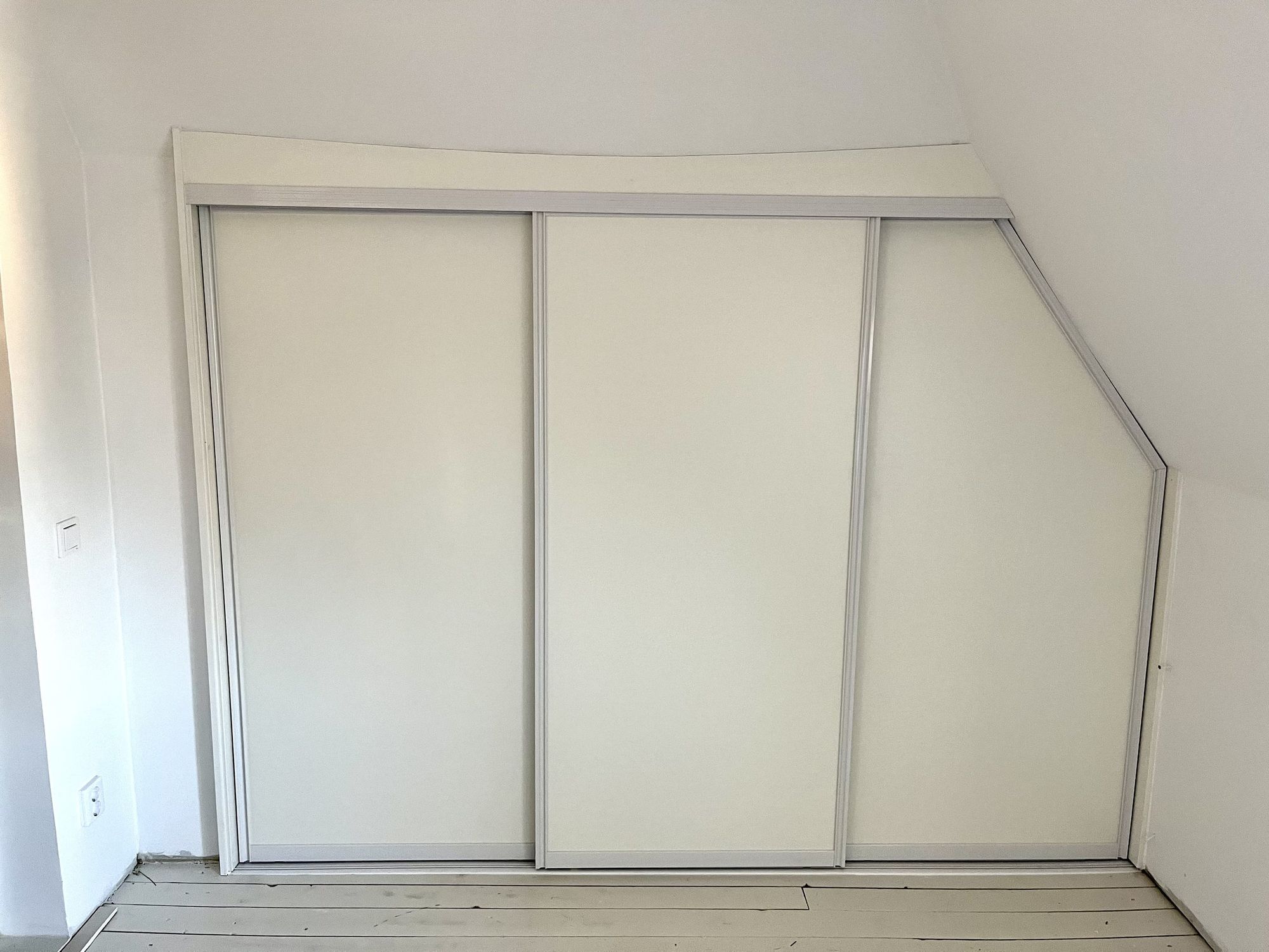White sliding doors with the top following the sloped ceiling