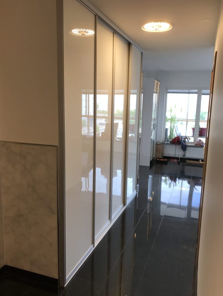 White sliding doors along a long glossy hallway