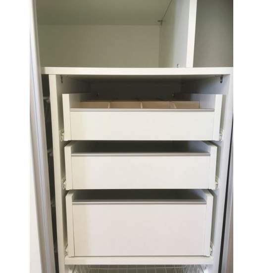 Three white drawers stacked in a wardrobe section, the top one with dividers.