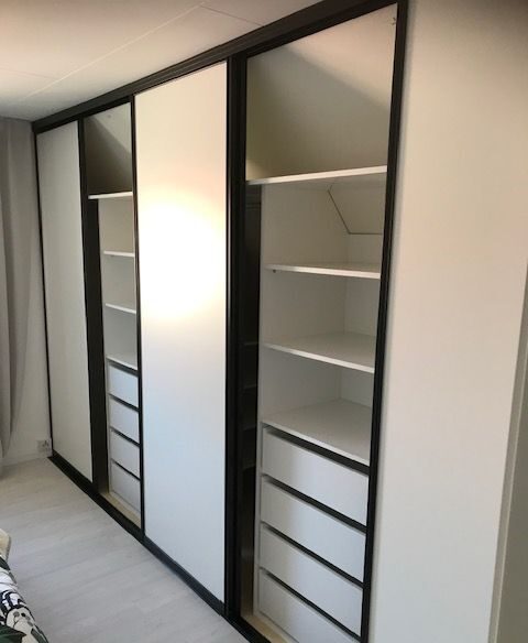 Bedroom wardrobe with shelves and drawers behind white sliding doors