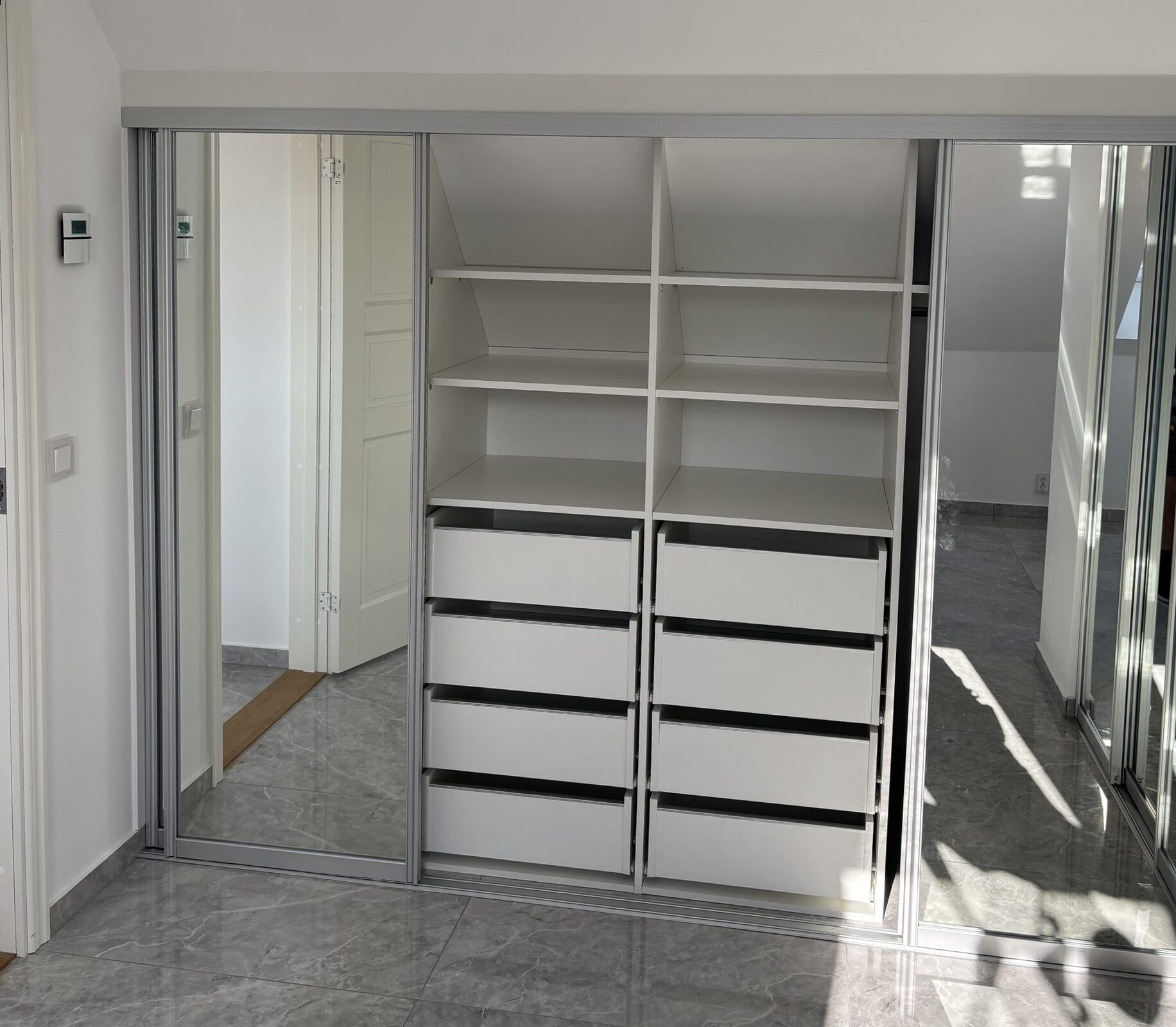 White shelves and drawers beside a mirror door