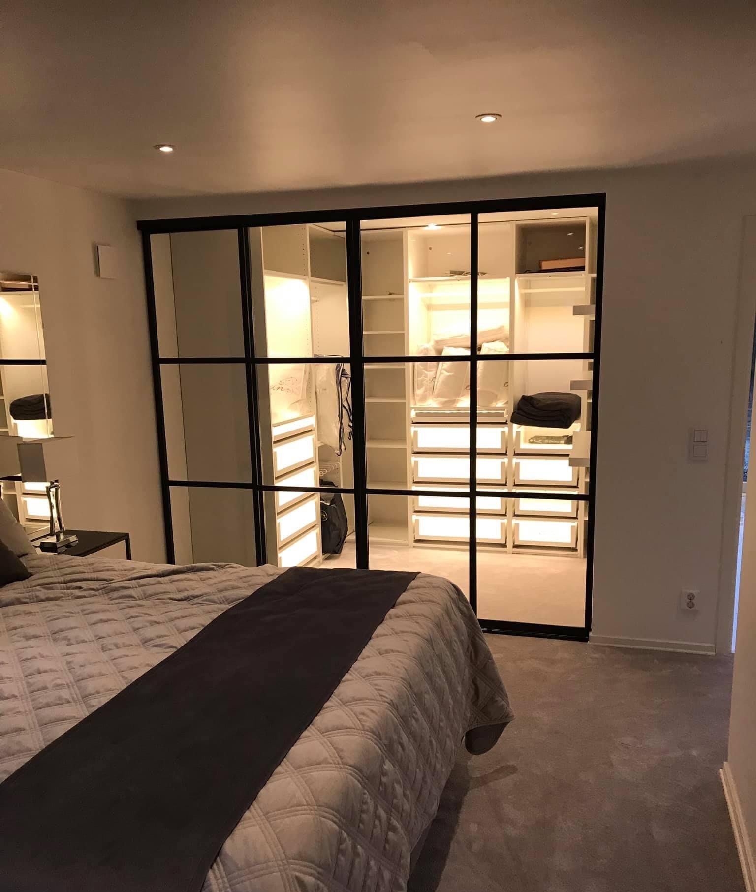 Black-framed glass wall, lit wardrobe beyond